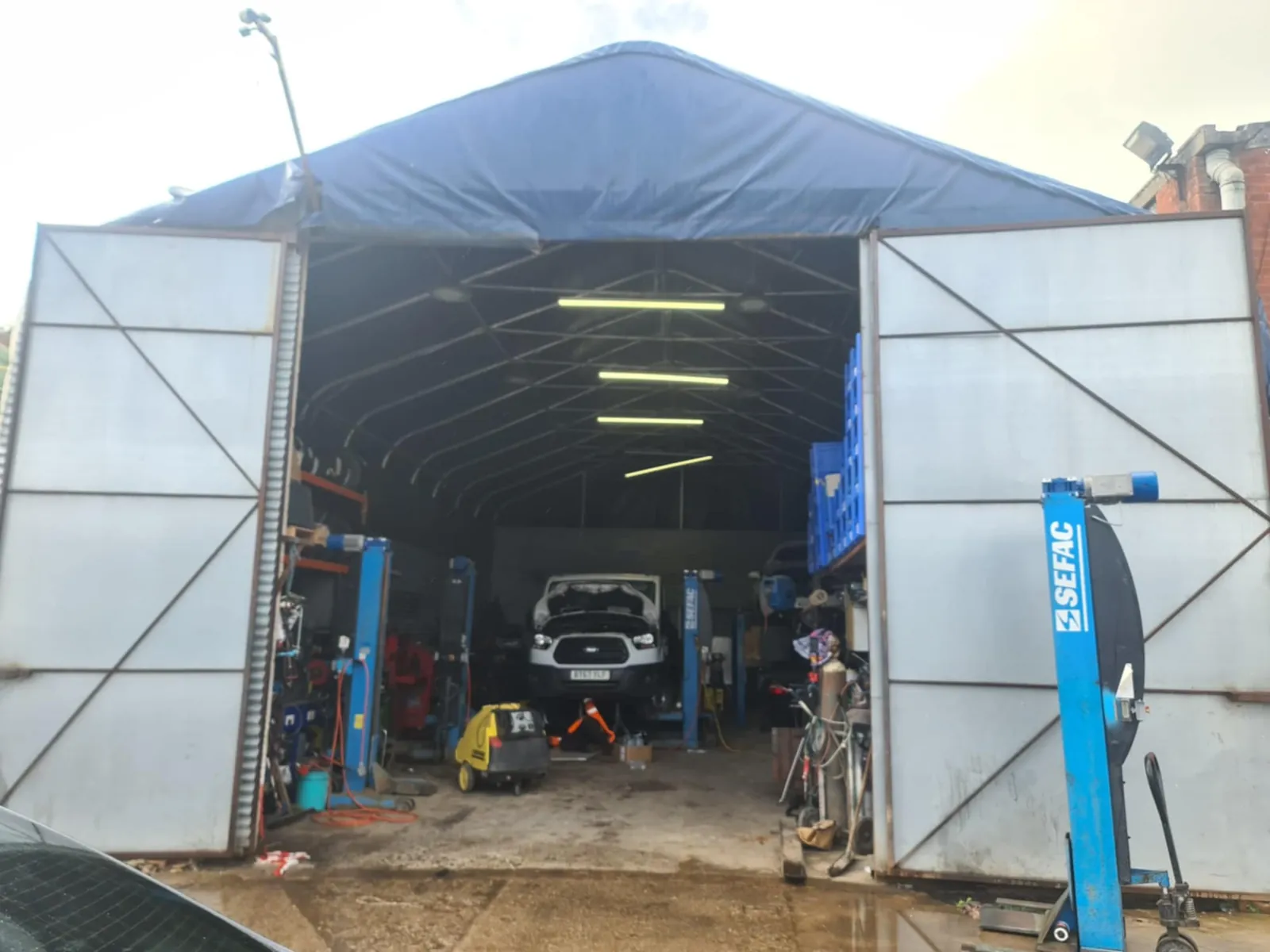 Open North West Tachographs workshop entrance with vehicle lifts and a van inside
