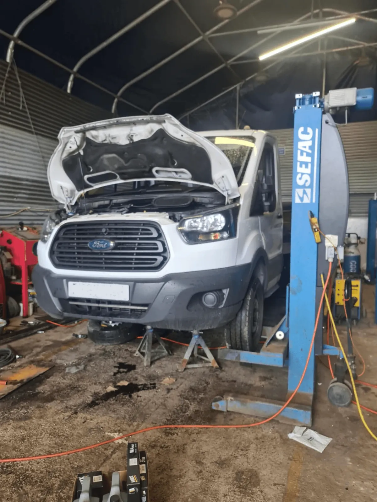 Van with its bonnet open on a workshop vehicle lift