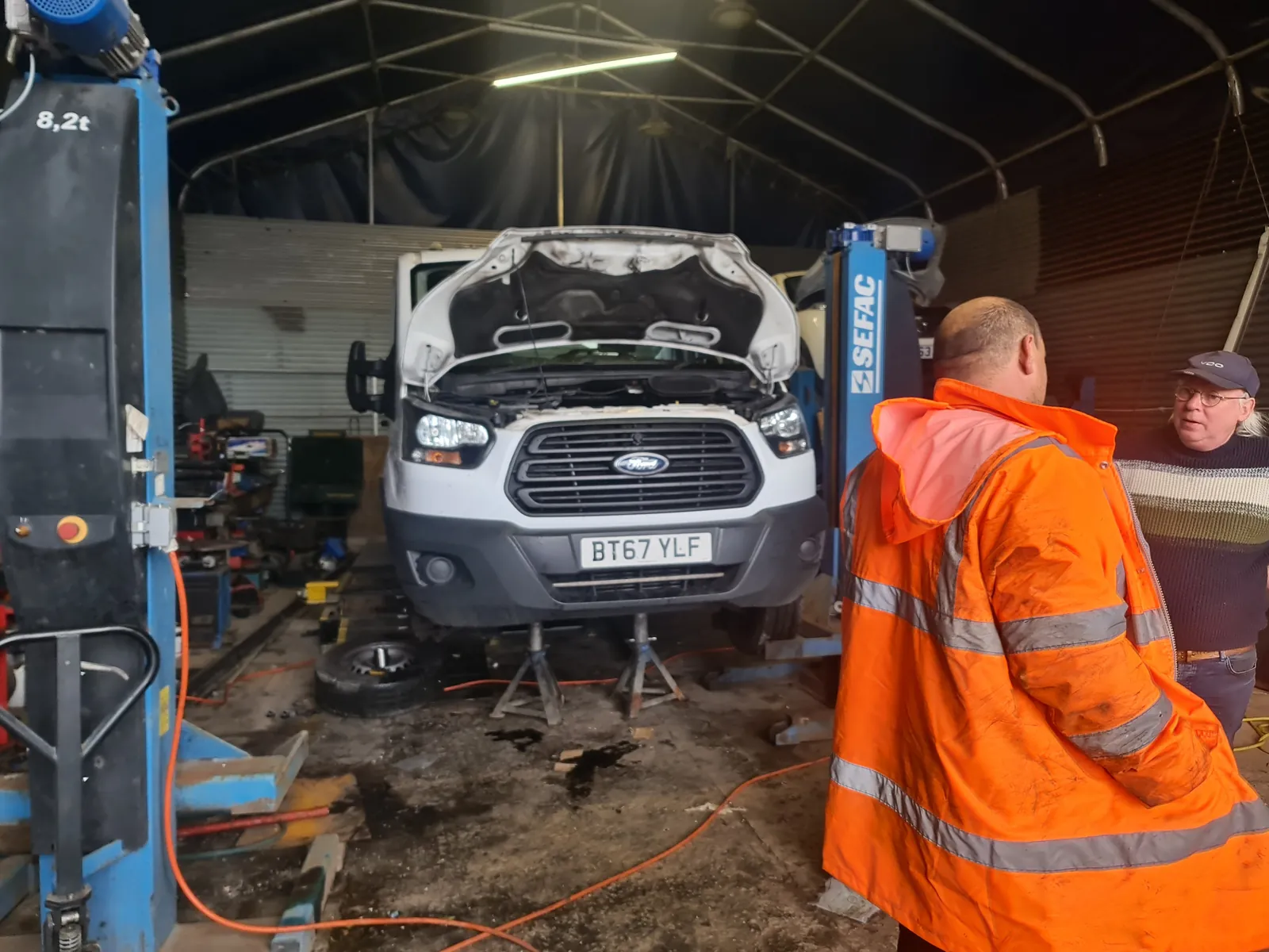 People beside a van with its bonnet open in the workshop